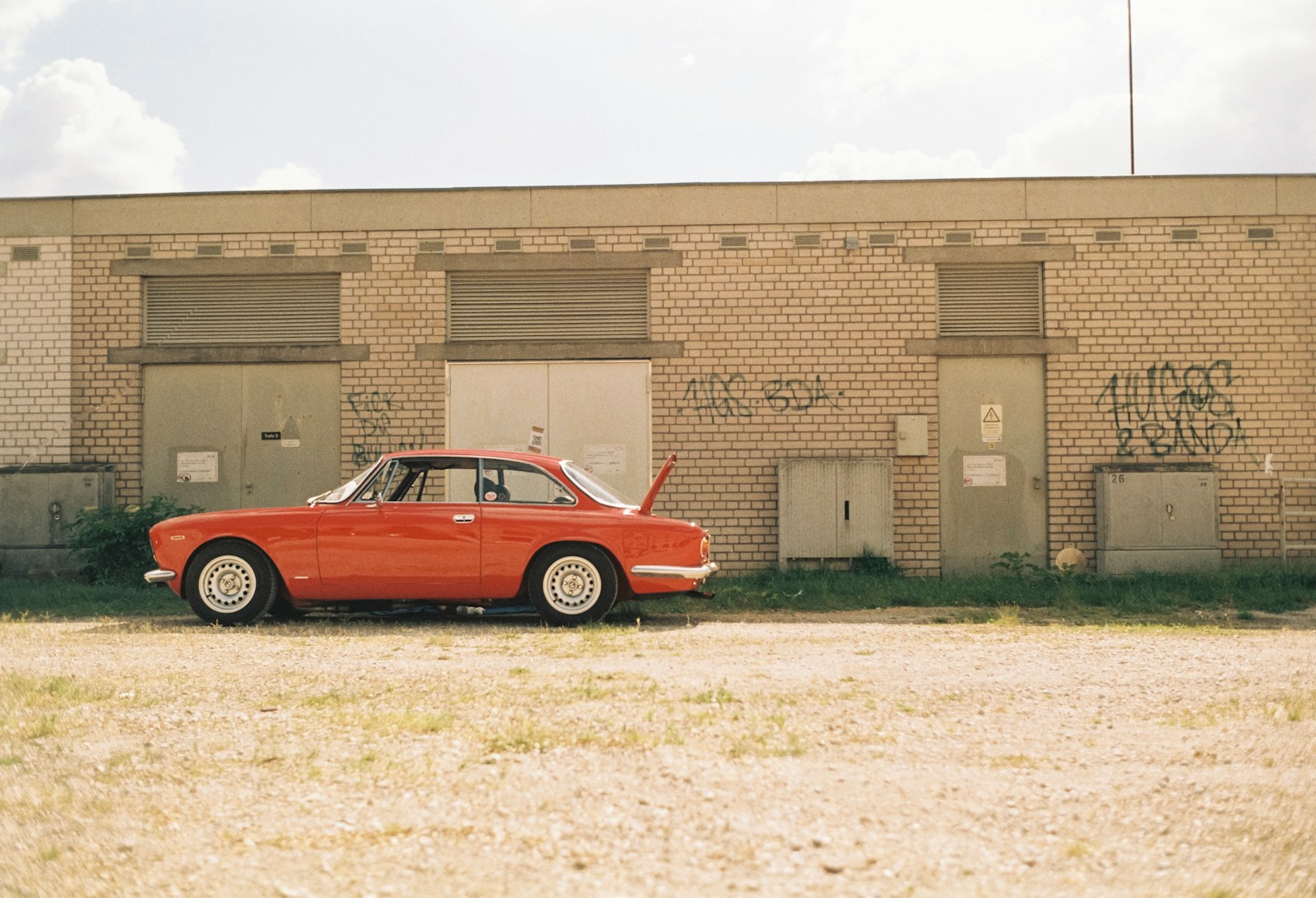 a red car parked in front of a brick building